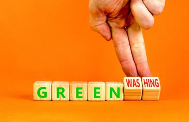 Mano su sfondo arancio che indica il fenomeno del greenwashing